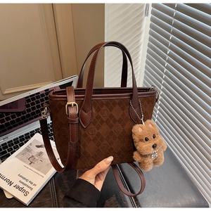 Detail of dark brown suede bucket bag with quilted patterns and cute dog charm attachment