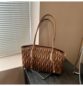 Detail of dark brown tote bag featuring luxury matelasse pleated texture and slender straps