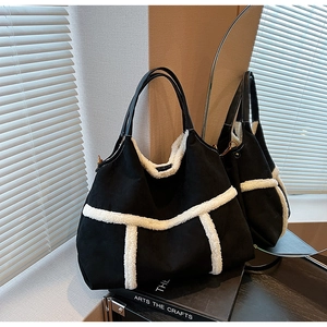 Detail of black tote bag with white faux shearling trim and leather handles in a mirror view
