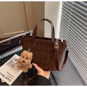 Detail of coffee brown suede tote bag with embossed textures and a cute dog charm
