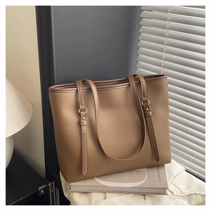 Detailed shot of brown litchi pattern tote bag with gold metal buckle and leather strap