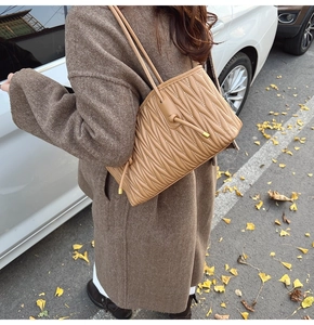 Detail of khaki matelassé pleated tote bag with drawstring knots and slim shoulder straps