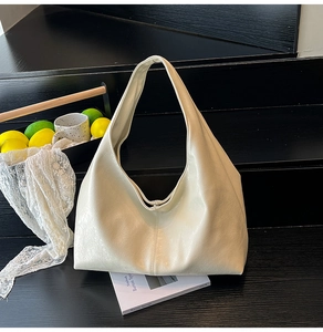 Detail view of cream leather tote bag with soft texture and wide shoulder strap