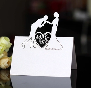 Detail of white laser-cut Mr & Mrs wedding place card with heart and couple silhouette