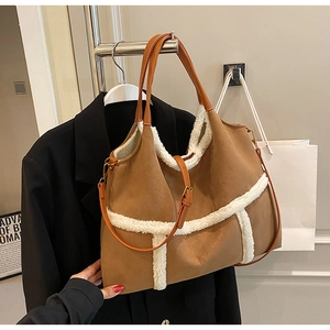 Detail view of large brown faux suede tote with white shearling trim and leather strap