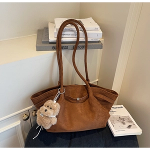 Braune Shopper-Tasche aus Wildlederimitat mit Teddy-Anhänger auf einem Kissen