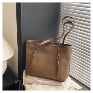 Close-up of dark coffee litchi grain leather texture and gold hardware on tote bag