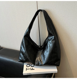 Detail of black glossy hobo bag with PU leather texture on a stylish studio background