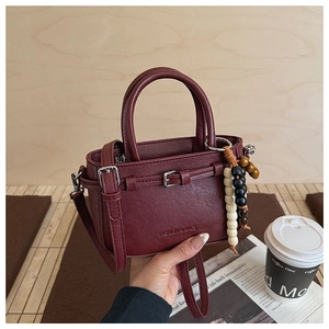 Detail of burgundy lychee grain mini handbag with wooden bead charm and long strap