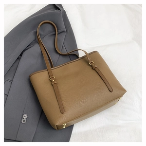 Detail of brown pebble leather tote bag with gold metal feet and adjustable long straps