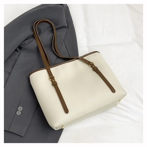 Detail view of large cream tote bag with litchi texture and brown leather straps