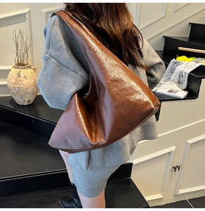 Detail of glossy brown oil wax leather hobo bag with high quality stitching on shoulder strap