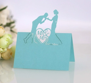 Detail of laser cut blue wedding place card with Mr & Mrs silhouette and heart design