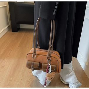 Détail d'un sac bandoulière vintage en daim caramel avec breloque ours et cuir poli
