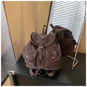 Detail view of vintage dark brown suede backpack with buckle straps and flap pockets