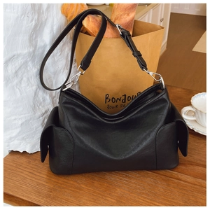Vue détaillée du sac à bandoulière en cuir noir avec sangle et poches latérales