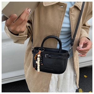 Detail of black mini square bag with beaded charm and embossed fashion text