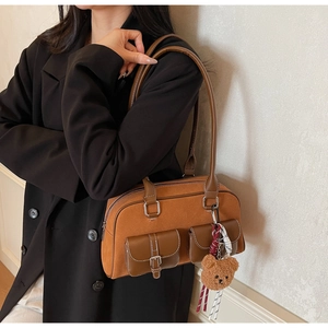 Détail d'un sac à bandoulière marron rétro avec deux poches et porte-clés ours mignon