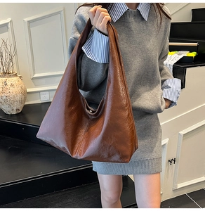 Deep brown large leather hobo bag with slouchy texture worn by model in a stylish setting
