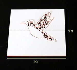 Macro detail of laser-cut bird place card showing intricate floral hollow patterns