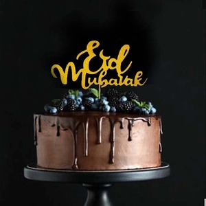 Golden glitter Eid Mubarak cake topper featured on a chocolate cake with berries