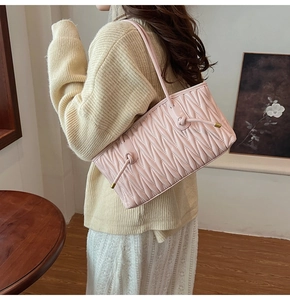 Detail of pink quilted Matelassé shoulder bag with golden hardware on a model