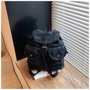 Detail of a vintage black suede backpack with flap buckle and symmetric front pockets