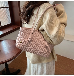 Detail view of pink pleated handbag with leather knots shown on a model's shoulder