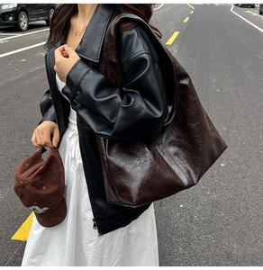 Detail of the oversized dark brown distressed leather hobo bag worn over the shoulder