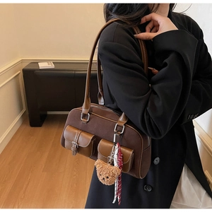 Détail d'un grand sac bandoulière en daim marron avec doubles poches et ours peluche