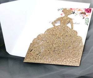 Detailed laser cut gold glitter wedding invitation featuring a hollow dress silhouette