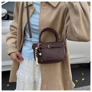Deep brown crossbody mini bag featuring a stylish bead charm shown on model