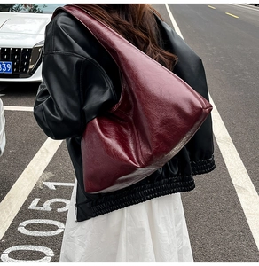 Detail of burgundy leather hobo bag with oily texture shown in street style outfit