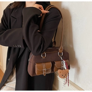 Sac Boston vintage marron en daim avec breloque ours porté par un mannequin