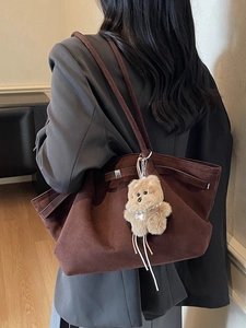 Braune Wildleder-Tragetasche mit Plüschwelpen-Anhänger und grauem Blazer
