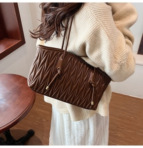 Detail view of brown quilted tote bag with drawstring knots and elegant matelasse texture