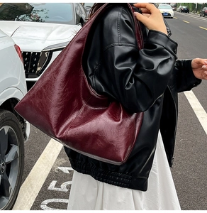 Detail of vintage dark red tote bag in oily waxed leather worn on the shoulder outdoors
