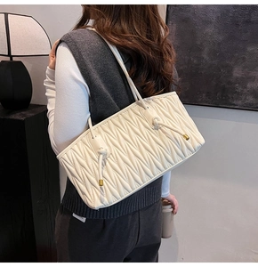 Detail of off-white quilted tote bag with wavy pleats and elegant knotted shoulder straps