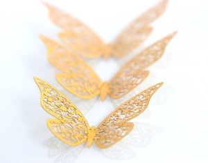 Macro view of 3D gold hollow butterflies with intricate floral laser-cut patterns
