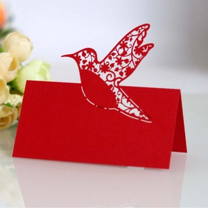 Elegant red laser-cut hummingbird place cards with floral details for wedding tables