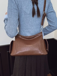 Sac bandoulière vintage en cuir marron avec poches latérales porté par un mannequin