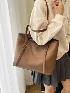 Brown litchi grain leather tote bag with shoulder strap shown on a model
