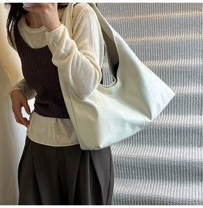 Minimalist white leather hobo bag shown in a styled urban setting on model's shoulder
