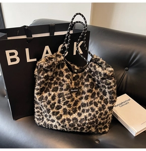 Chic leopard print plush tote bag with woven rope handles on a black leather background