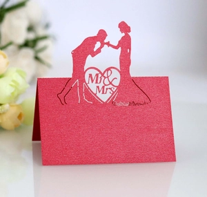 Macro view of laser-cut red pearlescent wedding place card with Mr & Mrs silhouette