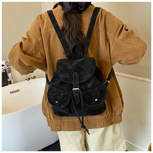 Close-up of black retro backpack featuring front buckled pockets and drawstring closure