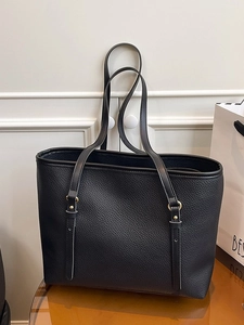 Minimalist black pebble leather tote bag with gold metal rings for daily commuting