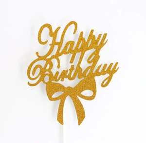 Detail view of a glittery golden Happy Birthday cake topper with a cute bow design