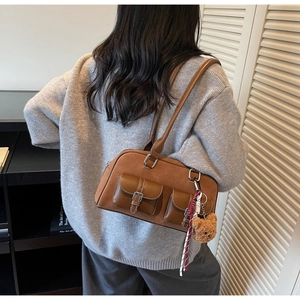 Détail d'un sac à bandoulière marron vintage avec poches et charm ours en peluche