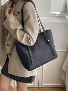 Black pebbled leather tote bag with long shoulder straps and gold metal ring accents